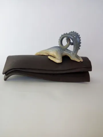 Bu eser AYŞE ERGÜNER tarafından 2021 yılında 36x17x20 cm ölçülerinde siyah çamur, porselen çamur, 1240°C, sırlı pişirim tekniği ile yapılmıştır.